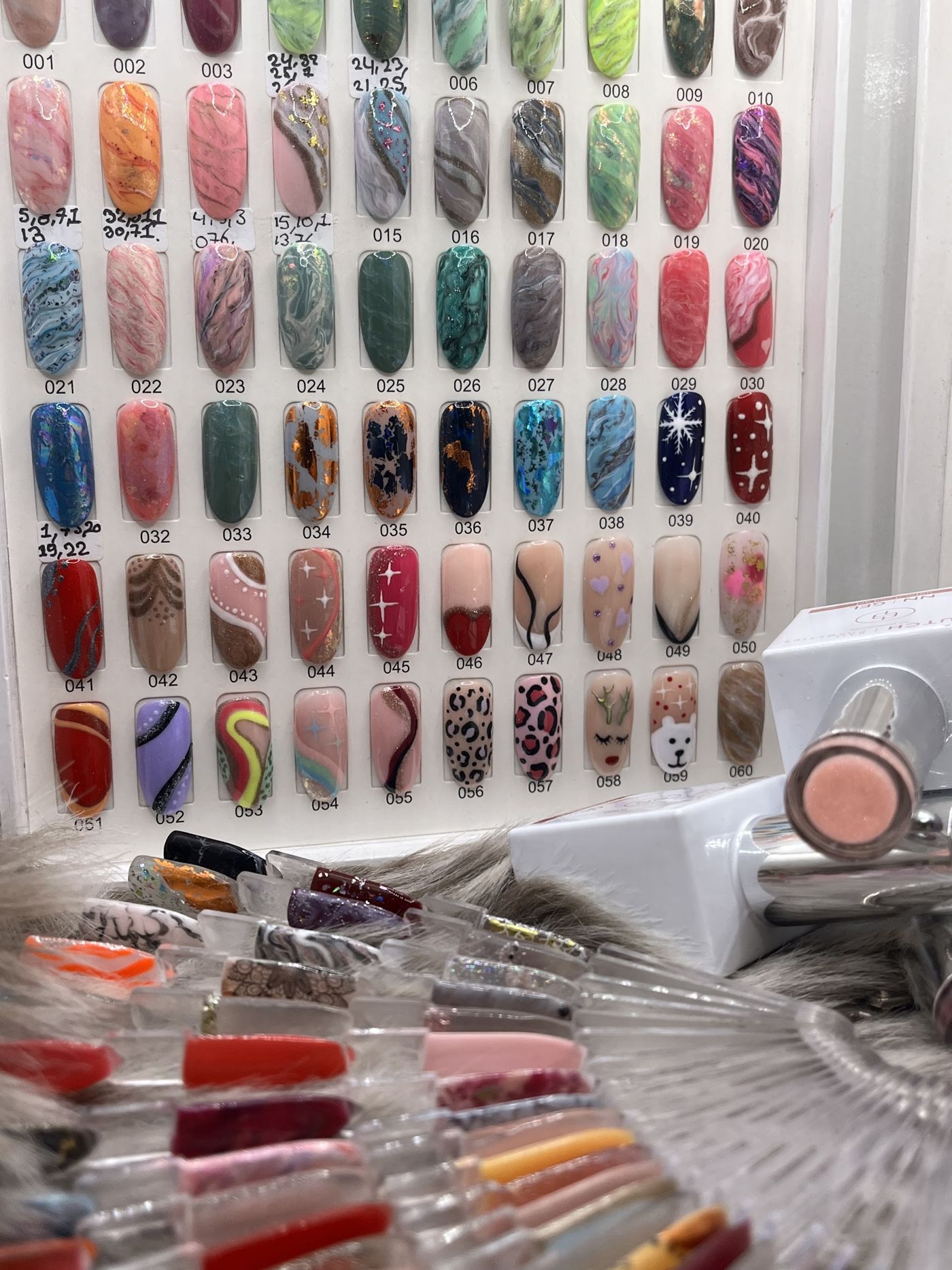 Wand met genummerde nailart voorbeelden en kleurstalen